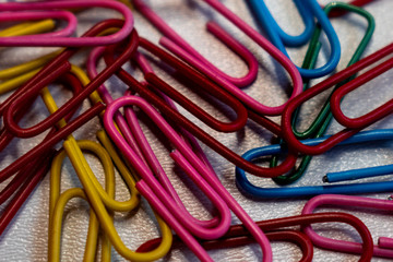 Multicolored paper clips scattered on white background. School office supplies paperwork documents organization stationery shopping concept.