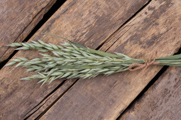 Young green wheat ears on wooden background. Sheaf of wheat ears on cracked wooden boards.