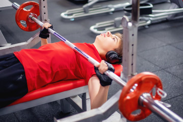 teen doing the bench press bar in the gym