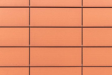 Fototapeta premium Texture of orange rectangular porcelain tiles. Building facade background.