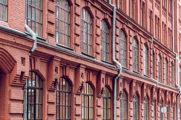 The facade of a classic red brick building with large windows. Brick architecture of a prestigious...