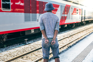 Behind the male criminals he was arrested and handcuffed, with locomotive on the plartform...