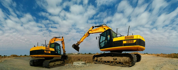 Two yellow excavators on a road under construction © Vyacheslav