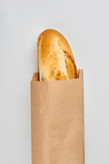 French baguette in kraft paper bag. French bread isolated on white background.