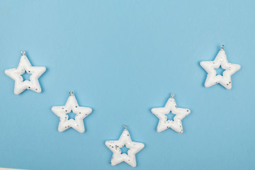 Holiday decorations. Creative composition made of white stars - Christmas tree toys on light blue...