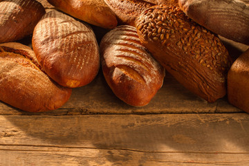 Pile of natural bread loaves on wooden background. Healthy artisan bread. Space for text.