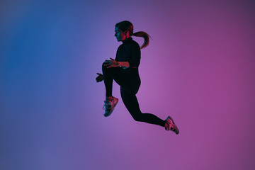 Fototapeta na wymiar Handsome woman with perfect body jumping against colorful trendy background. Young athletic girl in jump moment in studio