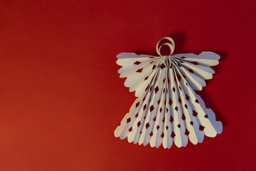 Paper angel on a red background. Origami art. Copy space.