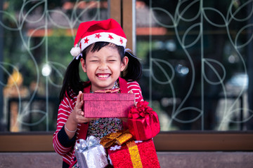 Exciting asian little girl  holding a lot of red gift box with smiling and happy at home.