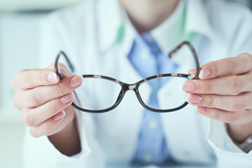 Optician giving new glasses to customer for testing and trying.
