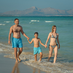 Happy family spending time on the beach on summer vacations.