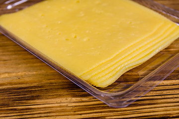 Sliced cheese and parsley in plastic container on wooden table