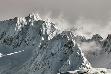 Snowy mountains in th French Alps, epic high mouintain landscape with cliffs piercing through clouds