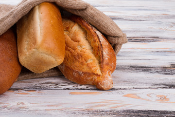 Freshly baked bread in burlap bag. Homemade bread in burlap sack on wooden table.