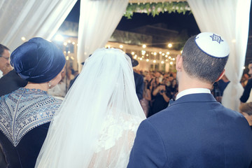Groom with the bride on a hupa of the Jewish wedding. Rear view.