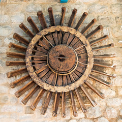 Old wooden wheel mill on the wall.