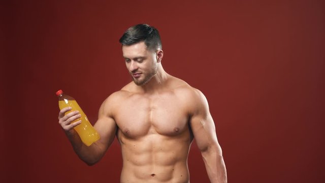 Healthy drink choices. Handsome man with sporty naked body chooses mineral water instead sweet one. Sportsman choosing healthy water on studio background.