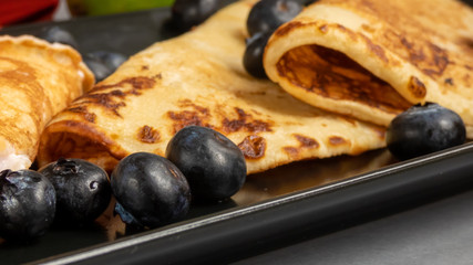  filled pancakes and blueberries on black plate