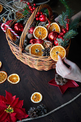 female hand collects a wicker basket with Christmas decorations and goods as a gift