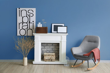 Comfortable armchair and fireplace near blue wall