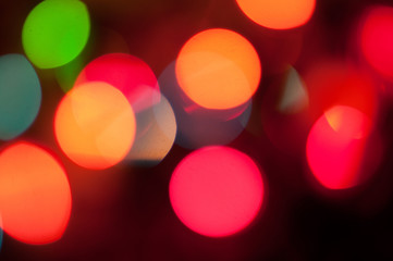 Glowing and festive colored light circles created from in camera and lens bokeh. Christmas fairy lights defocused giving a blurred effect. Background for design.