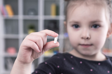 Little girl holding a pill addict. Focus on hands