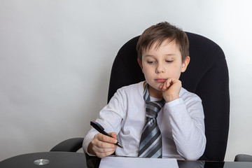 Close up of a cute brunette boy Presents being a director. The boy writes a letter In a white...