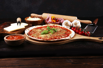 Pizza with tomatoes, mozzarella cheese, basil. Delicious italian pizza on wooden pizza board.