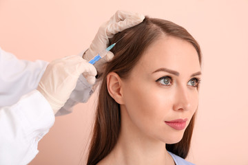 Woman with hair loss problem receiving injection on color background