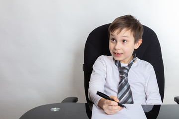 Close up of a cute brunette boy Presents being a director. The boy writes a letter In a white...