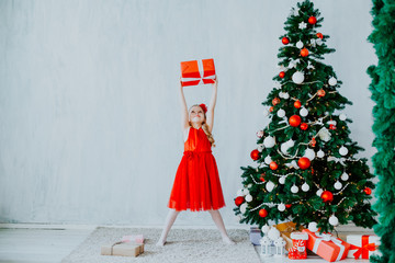 small girl in the red dress at the Christmas tree gifts new year holiday