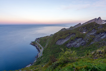 From top of the famous Reinebringen looking towards the road to Moskens in Lofoten, Norway. Blue hour during the midnight sun. Ocean and mountain view. Travel and hiking concept.