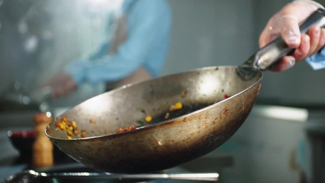 woman cooks vegetables with meat in frying pan slow motion