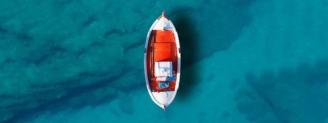 Luftdrohne von oben nach unten, ultrabreites Foto eines traditionellen Fischerbootes, das am weltberühmten Paradiesstrand der Insel Mykonos, Kykladen, Griechenland angedockt ist © aerial-drone