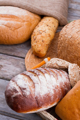 Assortment of fresh organic bread on wooden background. Assorted bread with flour.