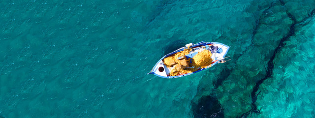 Fototapeta na wymiar Aerial drone top down ultra wide photo of traditional picturesque wooden fishing boat in Crete island beach with turquoise sea, Greece