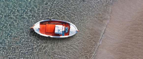 Aerial drone top down ultra wide photo of traditional picturesque wooden fishing boat in Crete island beach with turquoise sea, Greece
