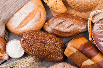 Rustic bread background. Assortment of baked wheat bread on wooden background.
