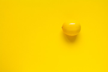 Ripe yellow lemon on a yellow surface, minimalistic background or concept - obrazy, fototapety, plakaty