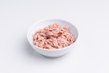 Canned tuna in a white bowl, isolated on white background; copy space, soft light, studio shot