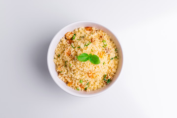 Delicious homemade vegetarian couscous with dates, raisins, parsley, tomato, lemon and olive oil in a white bowl on white background, Traditional Moroccan and Arabic Salad Tabbouleh