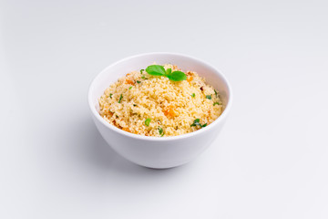 Delicious homemade vegetarian couscous with dates, raisins, parsley, tomato, lemon and olive oil in a white bowl on white background, Traditional Moroccan and Arabic Salad Tabbouleh