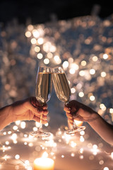 Hands of young couple clinking with flutes of champagne on xmas background © pressmaster