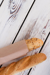 French bread on wooden background, top view. Freshly baked bread with sesame seeds. Space for text.