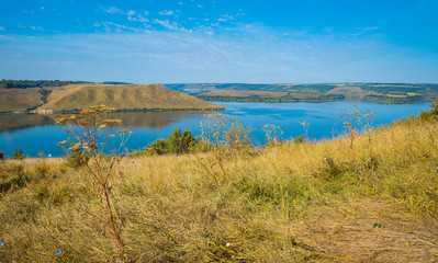 summer time grass hill land picturesque nature reservation scenic view with lake smooth calm water in clear weather