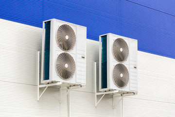 two double condensing units of air conditioner on blue and white metal industrial wall