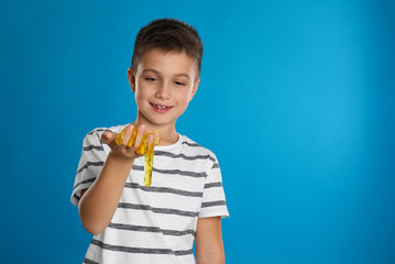 Little boy with slime on blue background, space for text