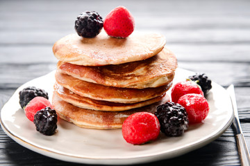 Plate with tasty sweet pancakes on table