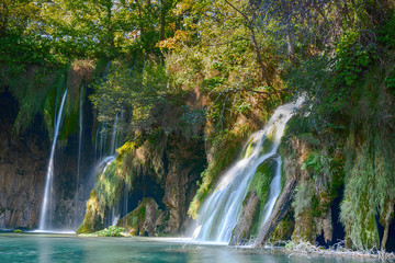 Last sunlight lights up the pure water waterfall on Plitvice National Park. Colorful spring panorama of green forest with blue lake. Great countryside view of Croatia, Europe.  
