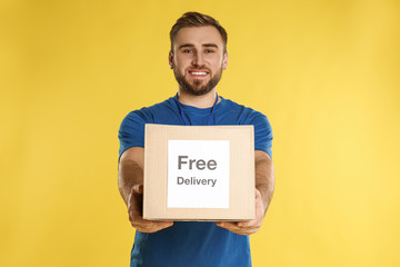 Male courier holding parcel with sticker Free Delivery on yellow background